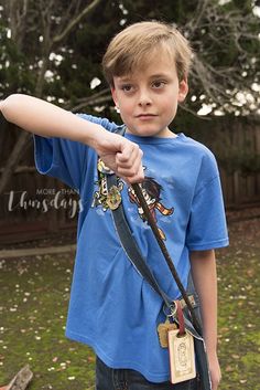 a young boy is pointing at something in the air with his arm extended and wearing a blue t - shirt