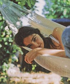 a woman laying in a hammock with her head resting on the back of it