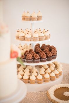 cupcakes are arranged on three tiered trays with white frosting and brown icing