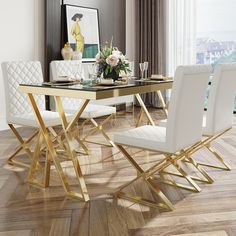 a dining room table with white chairs and gold trimmings on the top, in front of a large window