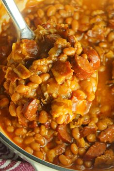 a spoon full of beans and meat in a pot with a cloth on the side