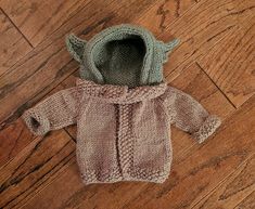 a knitted baby sweater with hood on the floor next to a pair of shoes