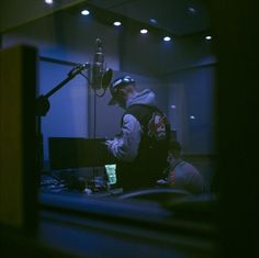 a man standing in front of a microphone with headphones on and wearing a hoodie