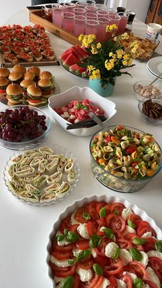 a table topped with lots of food and plates filled with sandwiches, salads and other foods