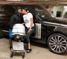 a man and woman kissing in front of a black suv