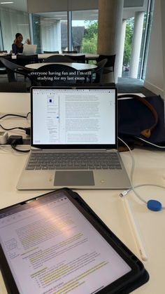 an open laptop computer sitting on top of a white table next to a black tablet