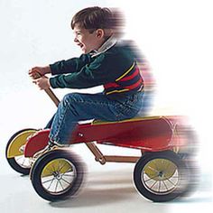 a young boy riding a red toy car