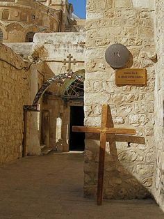 a wooden cross sitting next to a stone building