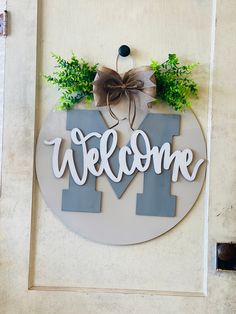 a welcome sign hanging on the side of a building with a bow and ribbon around it