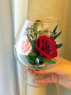 a person holding a glass bowl filled with flowers