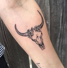 a cow skull with flowers on it's head is seen in this tattoo design