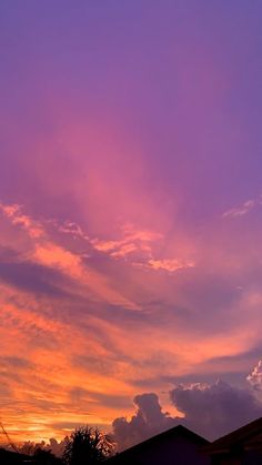 the sky is purple and orange as the sun sets in the distance behind some buildings