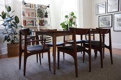 a dining room table with four chairs and a potted plant on the floor in front of it