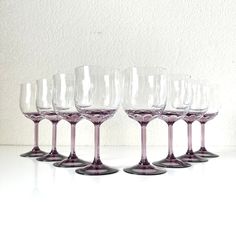 six wine glasses are lined up on a white counter top, with one empty glass in the middle