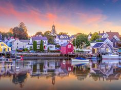 boats are docked in the water near houses and buildings at sunset or sunrise, as the sun sets