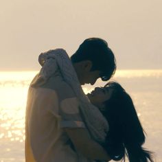 a man and woman standing next to each other near the ocean