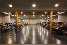 a garage filled with lots of different types of motorcycles and cars parked in rows next to each other