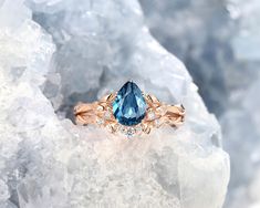 an engagement ring with a blue topazte surrounded by diamonds on some ice crystals