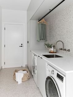 a laundry room with a washer and dryer next to a sink in the corner