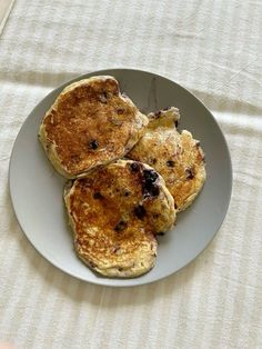 three pancakes on a white plate with blueberries