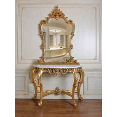 an ornate gold and black table with a mirror on it's top, in front of a white paneled wall