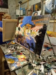 an artist's easel is covered with paint and other art supplies in the background