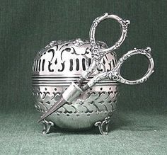 a pair of scissors sitting on top of a silver bowl