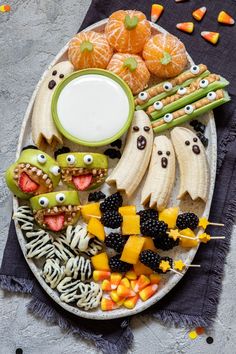 an assortment of halloween food on a platter with oranges, bananas and other foods