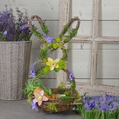 an arrangement of flowers and plants in baskets on a table next to a window sill