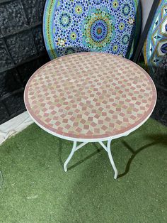 two chairs and a table in front of a brick wall with green grass on the ground