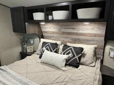 a bed with two pillows and some baskets on the headboard in a bedroom area