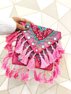 These boho banjara bags are intricately handmade using jute fabric, beads and coins. It comes with a magnet fastener as well as a zip to ensure full functionality.  We love how these gorgeous Boho Banjara bags is sewn together by hand with pretty tassels on each side. Each bag is fully lined with a zipper and an interior pocket. The deep rich colors and incredible embroidery make these bags a one of a kind! This boho bag is the perfect way to add a splash of color to your wardrobe. It goes pract Luxury Bohemian Pink Bag, Luxury Pink Bohemian Bags, Traditional Pink Beaded Bags, Bohemian Beaded Potli Bag For Gifts, Bohemian Beaded Potli Bag As Gift, Handmade Festival Pouch Bags, Bohemian Clutch With Handwork As A Gift, Traditional Handmade Pink Bags, Bohemian Pouch Bag For Festival