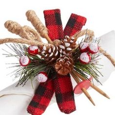 a red and black plaid ribbon with pine cones on it is tied to a napkin