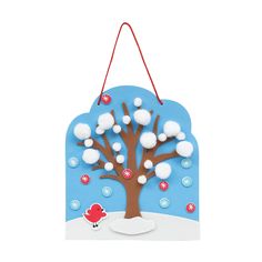 a paper cutout of a tree with snow on it and a red bird sitting in the foreground