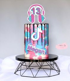 a birthday cake with the number thirteen on it and headphones in pink, blue, and purple