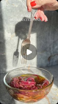 a person is holding a fork over a bowl of food with red onions in it