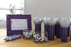 some purple candles are sitting on a table next to other items and a framed sign