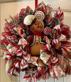 a christmas wreath with a teddy bear and candy canes hanging from the front door