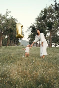 a woman and child in a field with the number one balloon