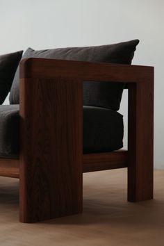 a wooden chair with two black pillows on it's back and armrests