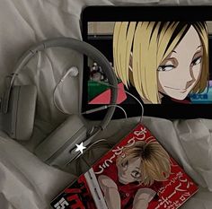 an electronic device with headphones on top of it next to a book and earbuds