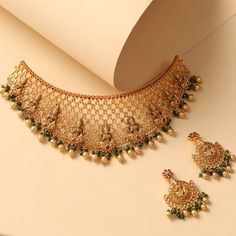 Description The Shriya antique choker from Tarinika’s bridal jewelry catalog is a stunning piece of art that will enhance your bridal party look. This Lakshmi motif choker has cz stones, and gold drop balls adorned on the antique gold base with regal antique nakshi elements combined with filigree patterns. A must-buy for your traditional occasions. Details & Specifications: Materials used: Brass Alloy with Antique Gold Plating Weight – Choker 92.56 gm, Earrings 19.88 gm Length – Choker 20 cm, Ea Bridal Choker Necklace With Intricate Design For Celebration, Intricate Design Choker For Receptions And Festivals, Intricate Design Choker For Reception And Festivals, Bridal Choker Necklace With Intricate Design For Festive Occasions, Festive Temple Jewelry Choker For Reception, Bridal Choker Necklace With Intricate Design For Reception, Intricate Choker Bridal Necklace For Reception, Festive Bridal Choker Necklace With Intricate Design, Festive Bridal Choker With Intricate Design