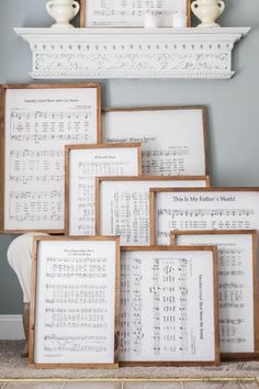 several framed music sheets are stacked on top of each other in front of a fireplace mantel