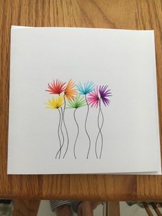 three colorful flowers are in a row on a white card with black ink and watercolor pencils