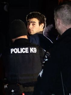 two police officers standing next to each other in the dark with their backs turned towards one another