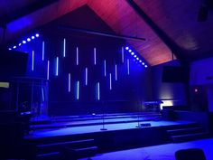 an empty stage lit up with blue lights in the middle and purple lighting on the ceiling