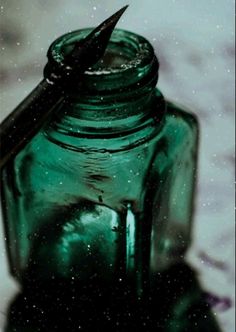 a green glass jar with a black ink pen sticking out of it