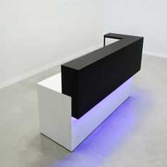 a black and white reception table with blue lights on the bottom shelf in an empty room