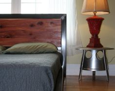 a bed sitting in the middle of a room next to a lamp on a table