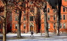 a person walking in front of an orange building with trees and snow on the ground